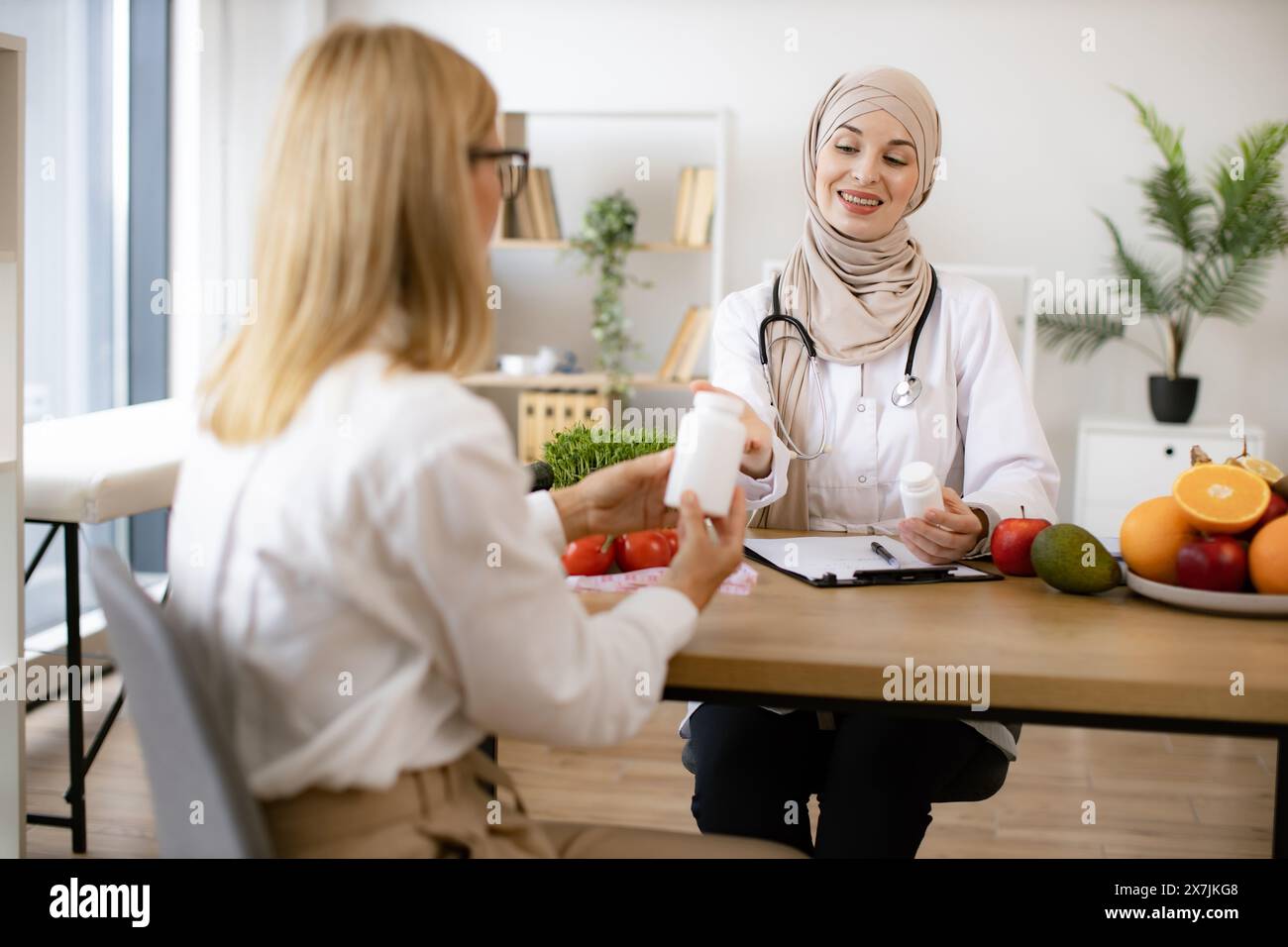 Mature Caucasian lady receives consultation on healthy eating. Muslim woman nutritionist makes plan for treatment of gastrointestinal tract using vita Stock Photo