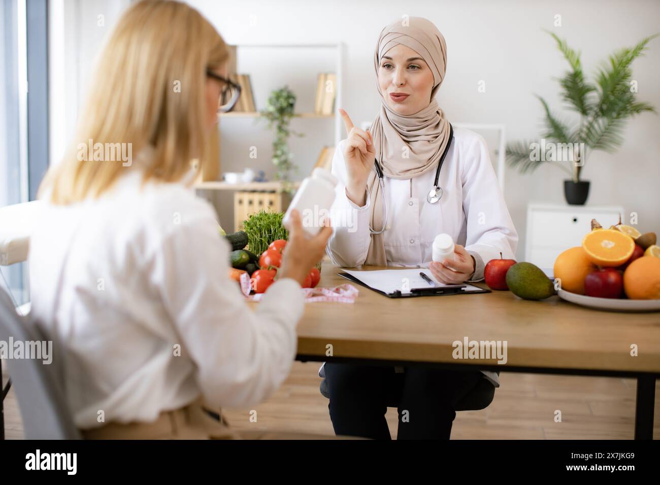 Mature Caucasian lady receives consultation on healthy eating. Muslim woman nutritionist makes plan for treatment of gastrointestinal tract using vita Stock Photo