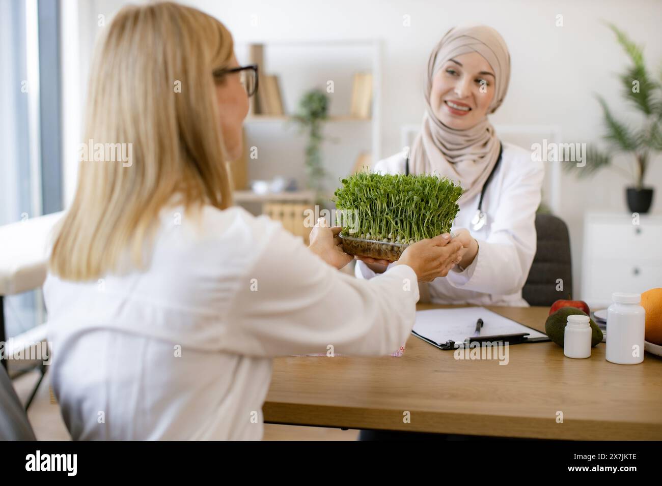 Arab female doctor makes treatment plan for gastrointestinal tract sitting at table in modern clinic. Professional nutritionist talks to patient about Stock Photo