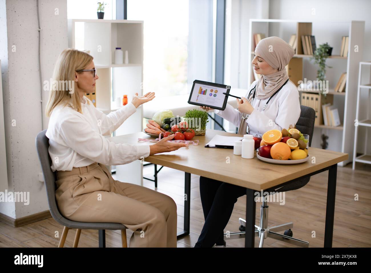 Arab female doctor makes treatment plan for gastrointestinal tract in modern clinic. Professional nutritionist tells patient about benefits of healthy Stock Photo