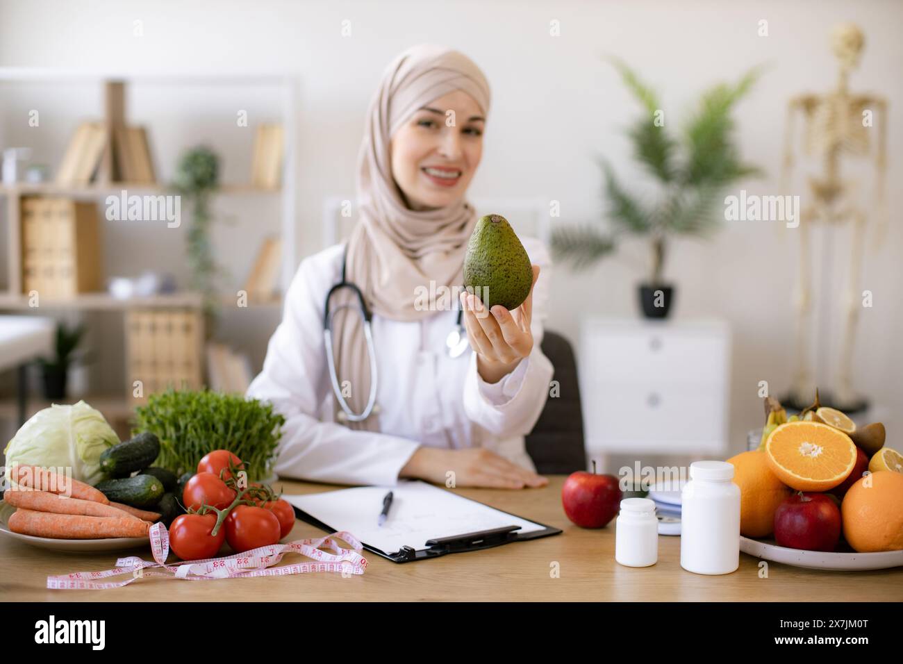 Happy female writing prescription for patients proper healthy diet. Arabian female nutritionist making healthy eating plan and calculating calorie con Stock Photo