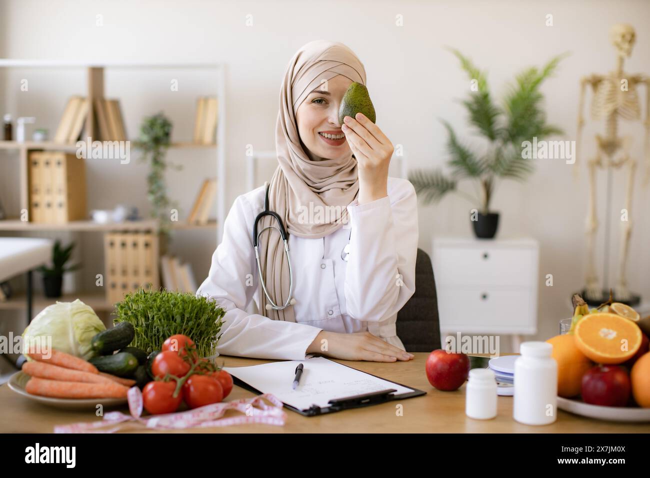 Happy female writing prescription for patients proper healthy diet. Arabian female nutritionist making healthy eating plan and calculating calorie con Stock Photo