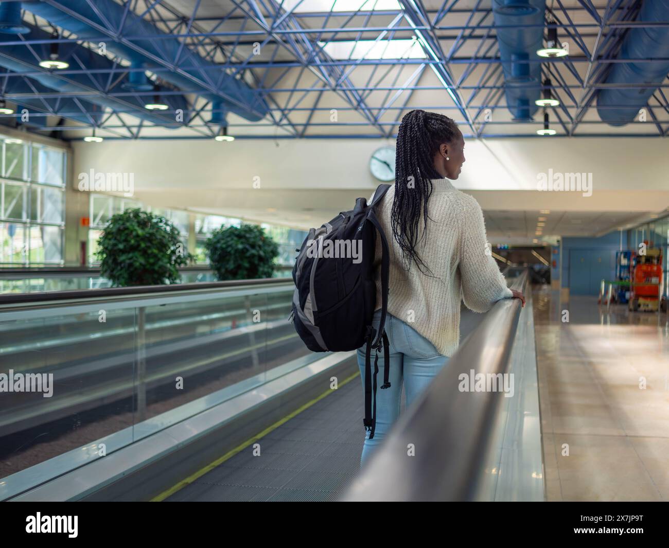 A young woman on a moving walkway inside an airport using her phone Stock Photo