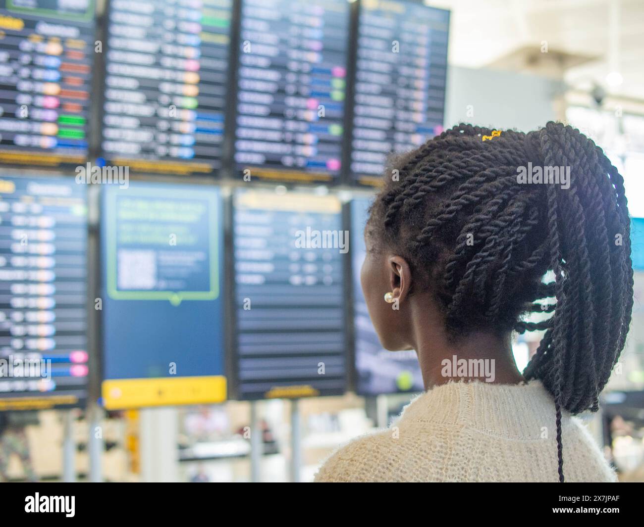 A young woman traveling alone checking the information on the airport screens. Stock Photo