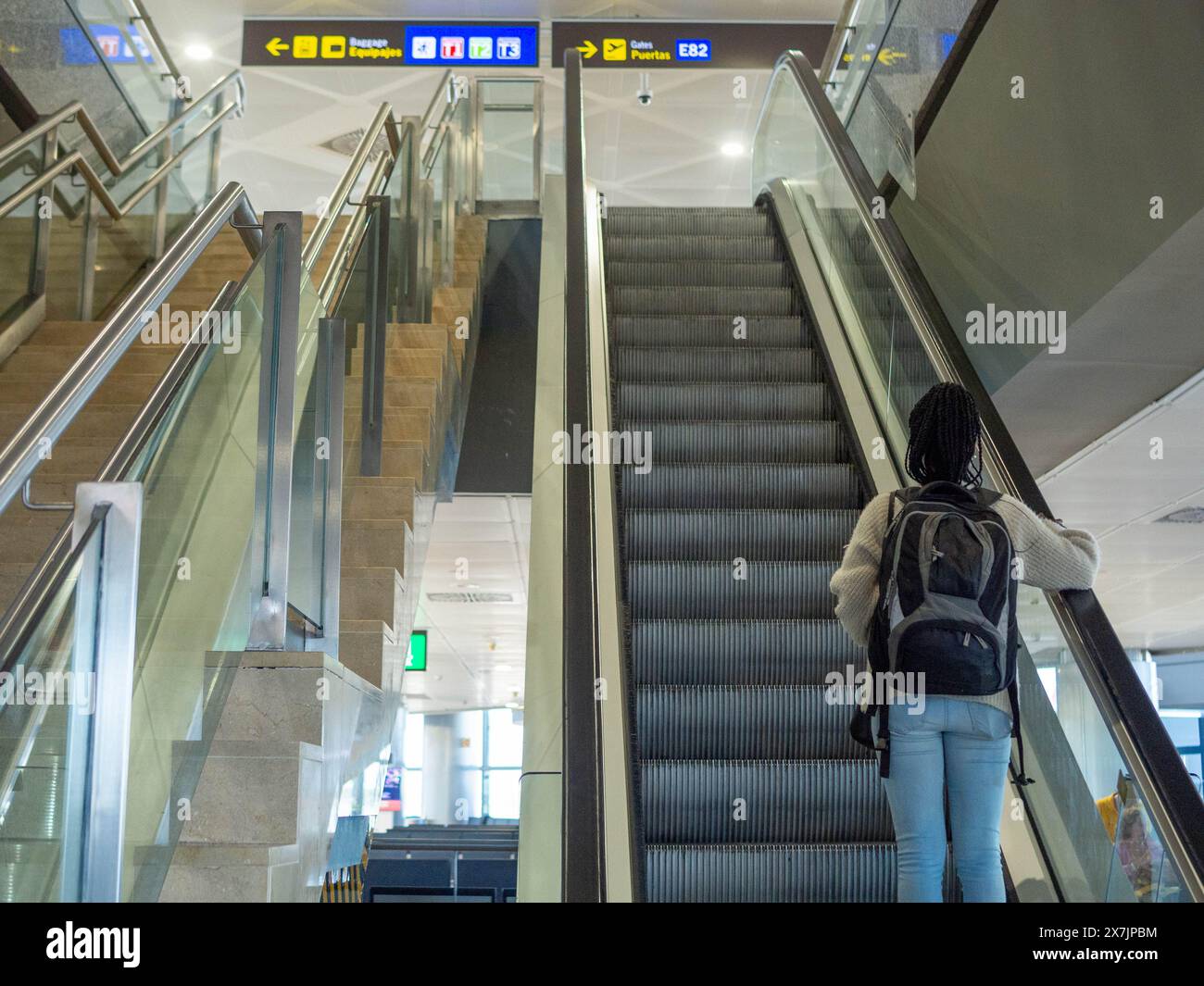 A young woman using the escalator at the airport Stock Photo