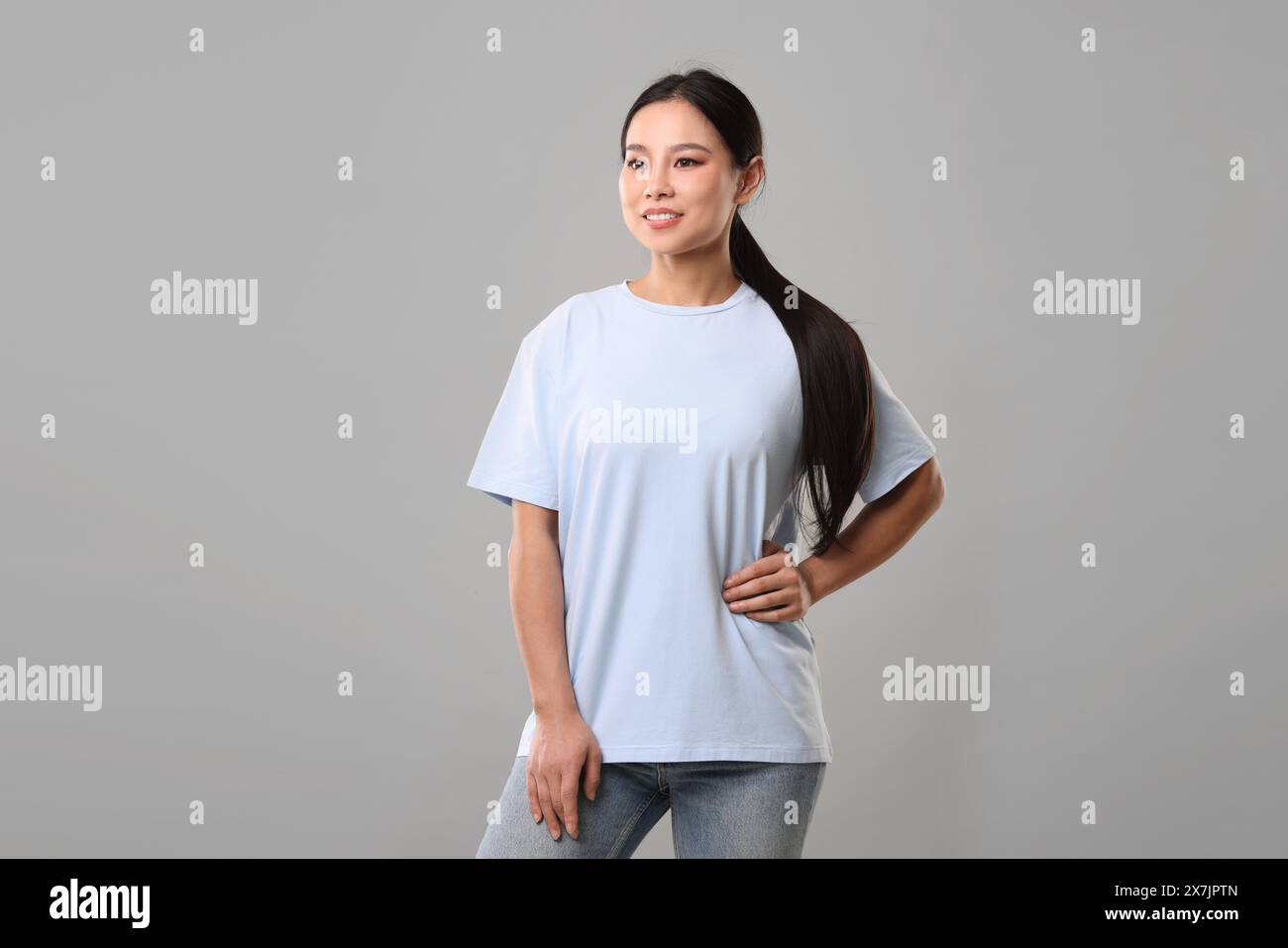 Woman wearing light blue t-shirt on grey background Stock Photo