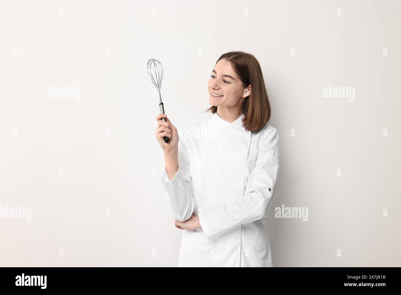 Professional chef with whisk on light background Stock Photo - Alamy