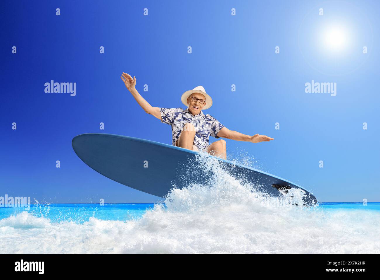 Elderly man riding a surfboard on a wave in the sea Stock Photo