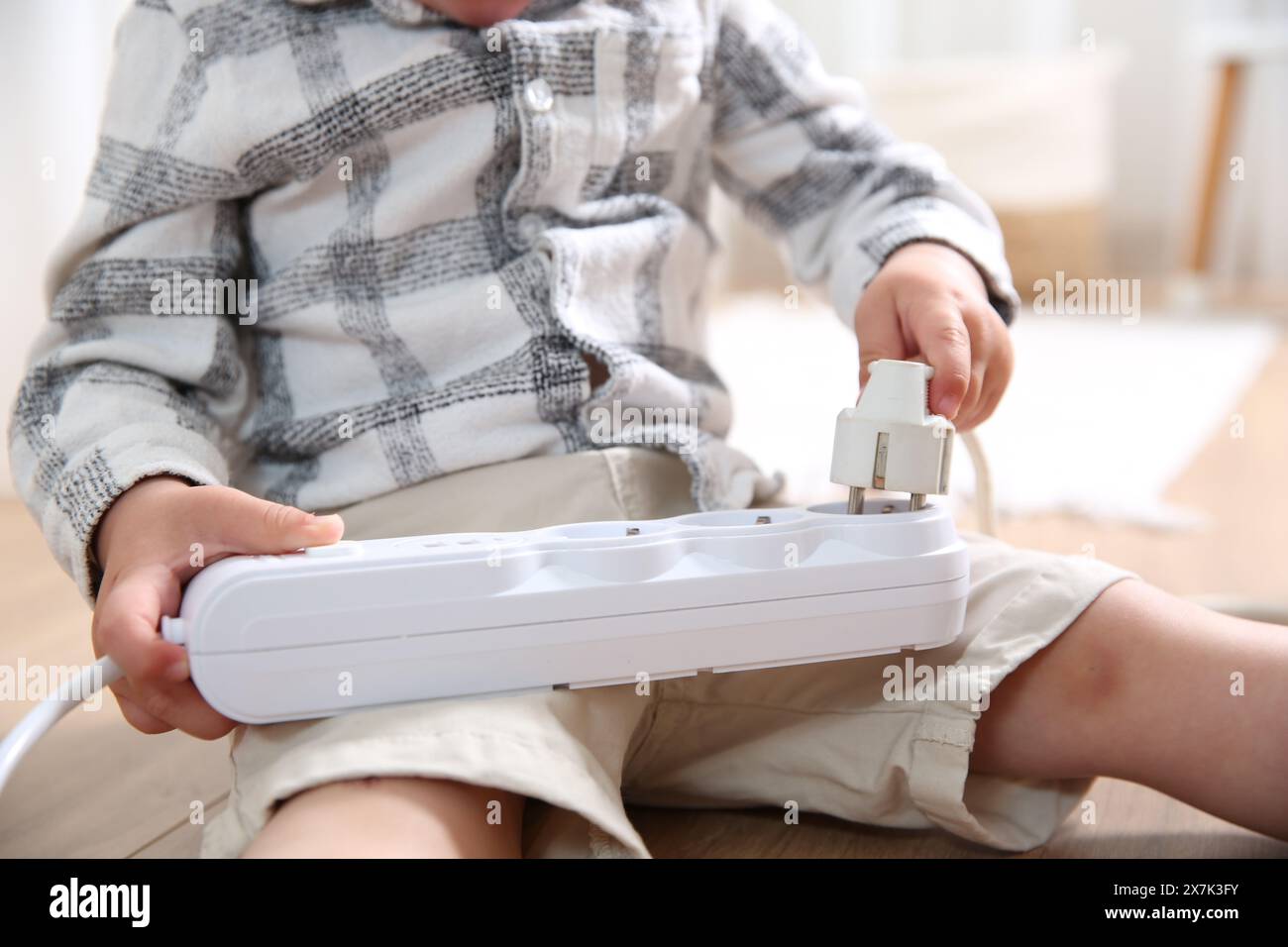 Little child playing with power strip and plug on floor indoors ...