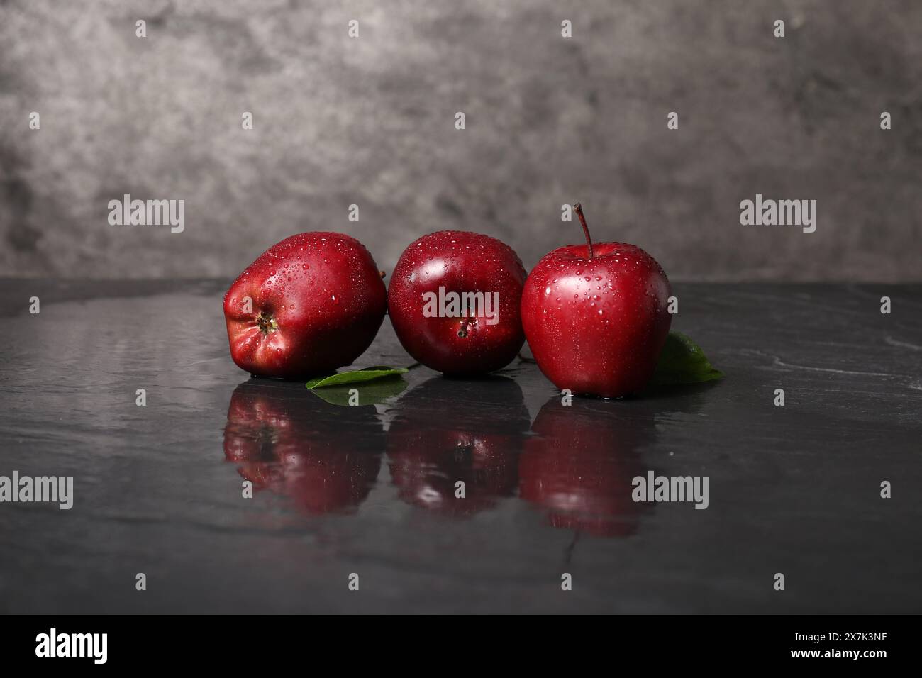 Wet red apples on dark grey table Stock Photo