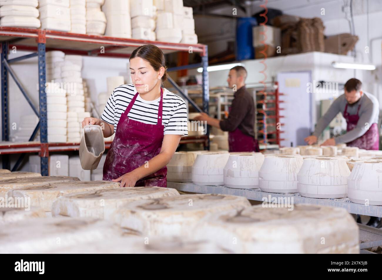 Female artisan pouring slip into casting molds in Stock Photo
