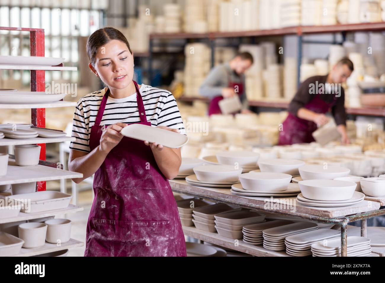 Female Ceramicist Examining Batch Of Slipcast Pottery In Workshop Stock