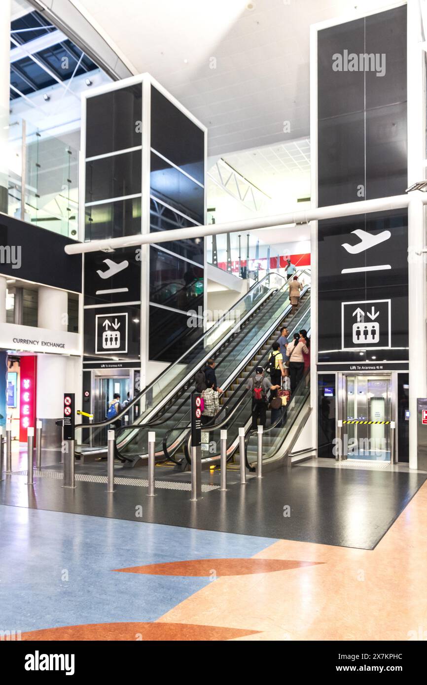 Auckland, New Zealand - February 21, 2024: Travelers using the escalator inside Auckland International Airport. Stock Photo