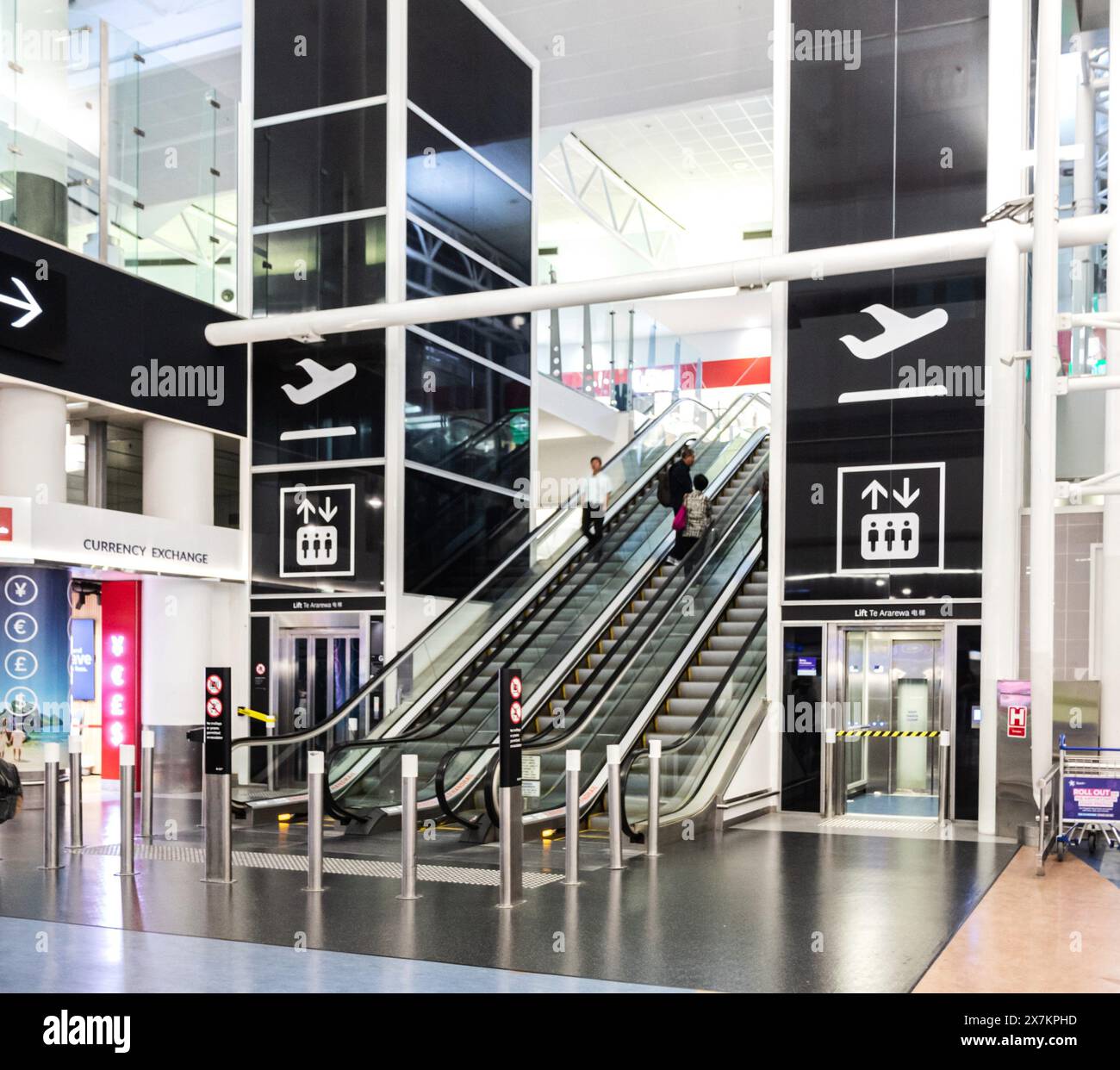 Auckland, New Zealand - February 21, 2024: Travelers using the escalator inside Auckland International Airport. Stock Photo