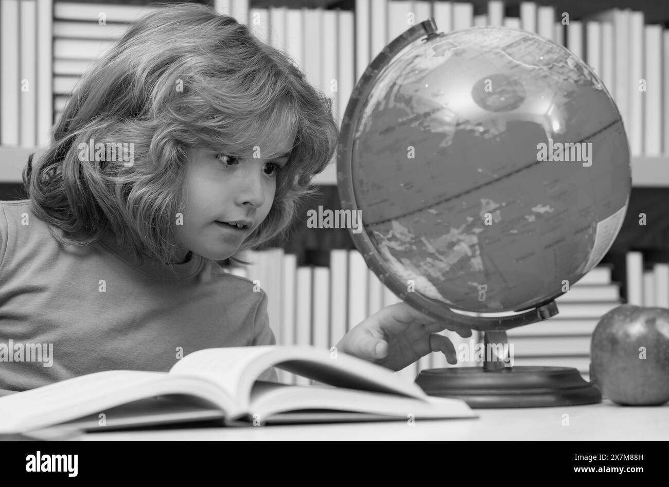 School kid looking at globe in library at the elementary school. Child
