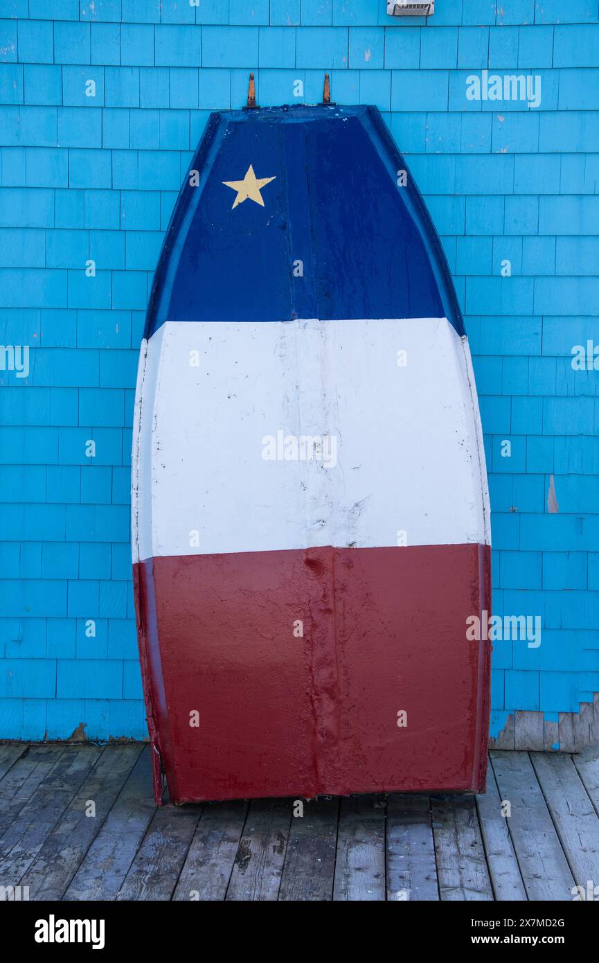 Acadian flag painted on the bottom of a boat leaned against a building in Shediac, New Brunswick, Canada Stock Photo