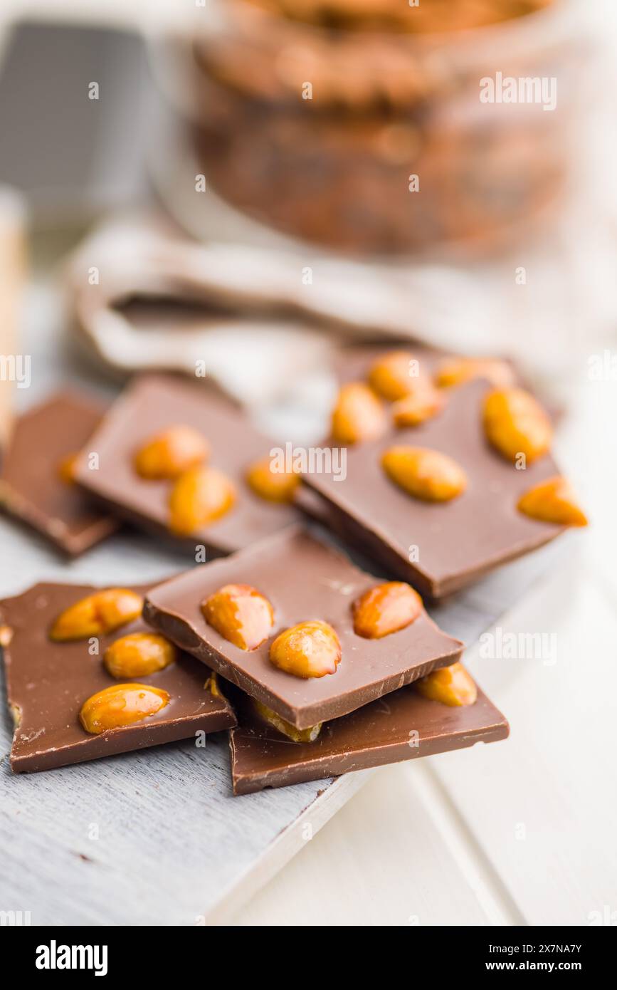 Broken chocolate bar with almonds on a kitchen table. Stock Photo