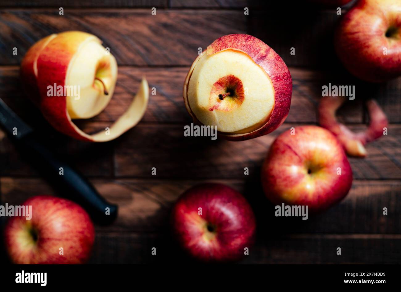 peeling red apples on a wooden surface Stock Photo