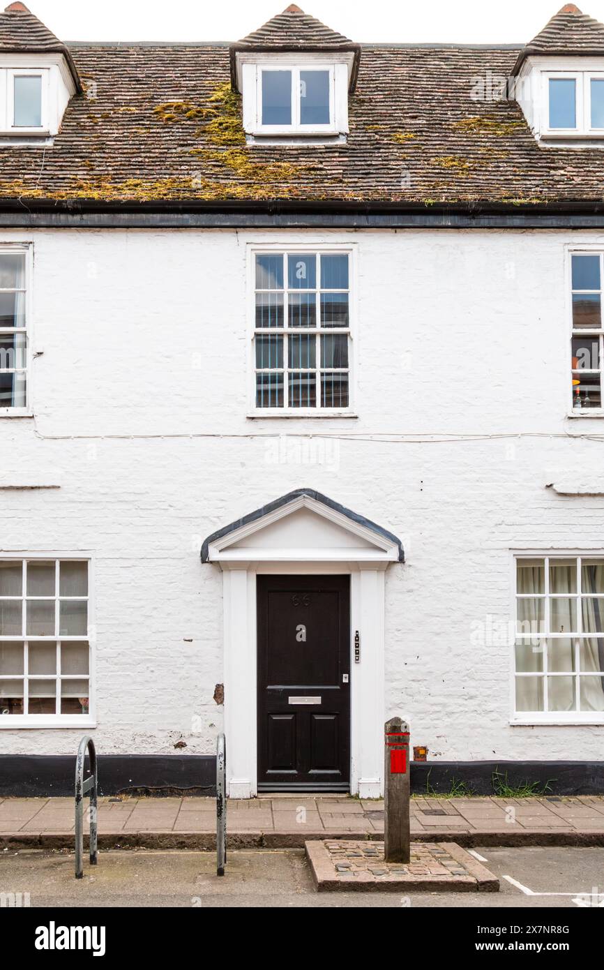 Front view of a Grade II listed traditional white brick townhouse with a black door and dormer windows on the roof. King St, Cambridge, England, UK Stock Photo