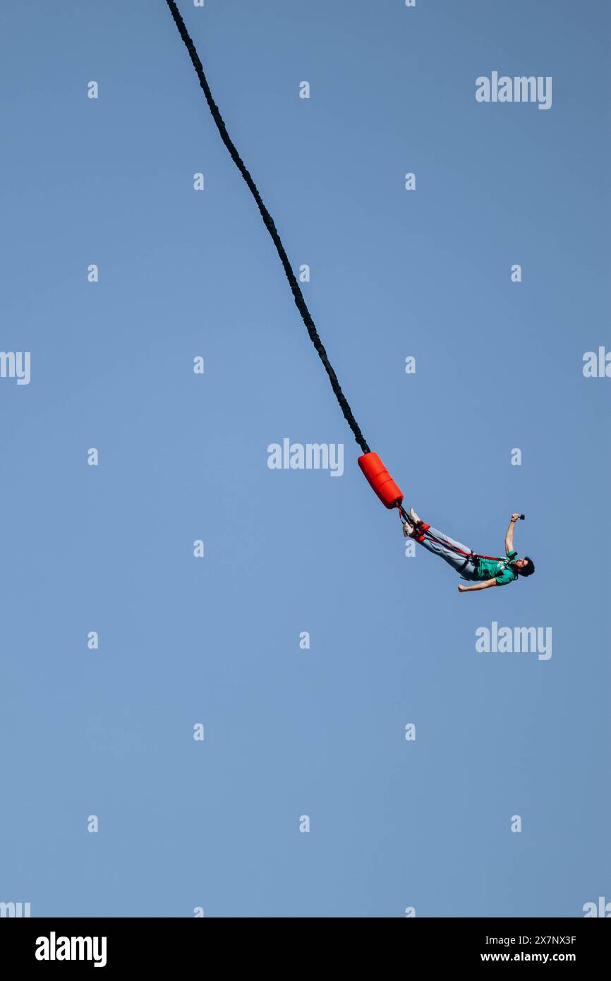 Bungee jumping from a great height while connected to a large elastic ...