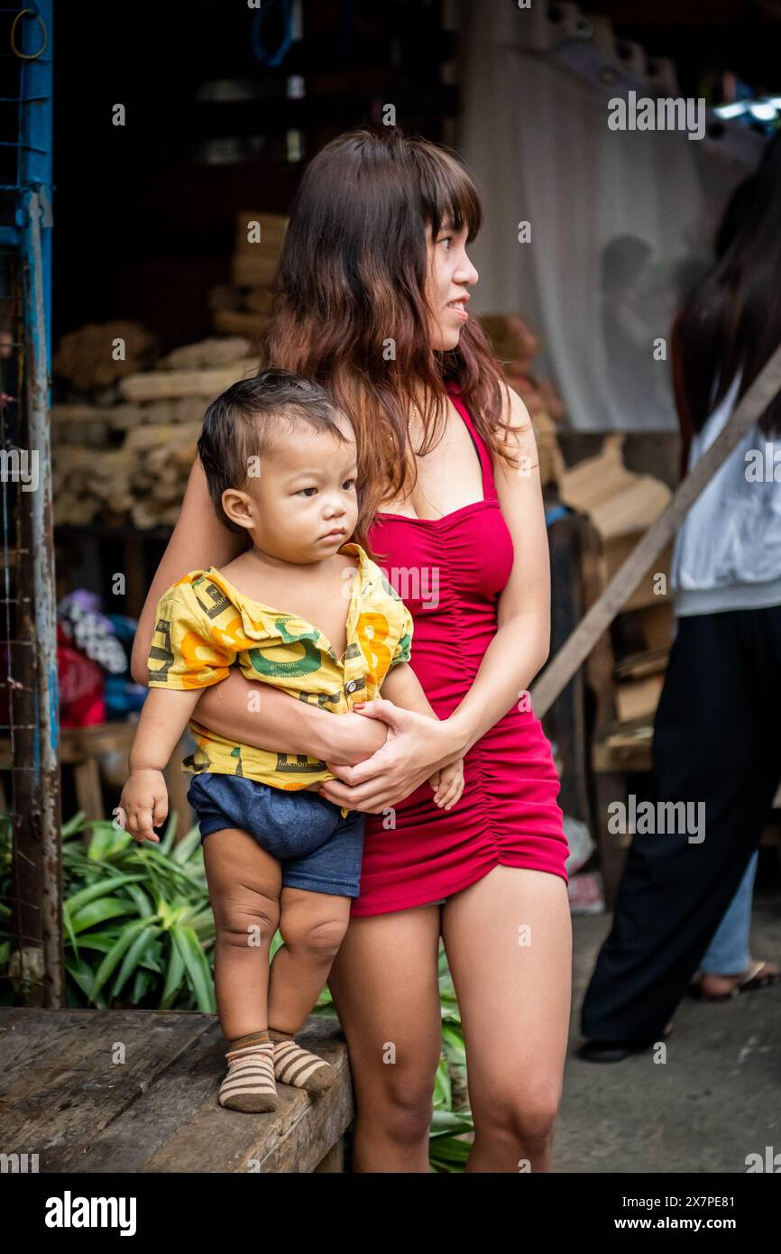 A young Filipino mother and daughter watch life go by in the Tondo District Manila, The Philippines. Stock Photo