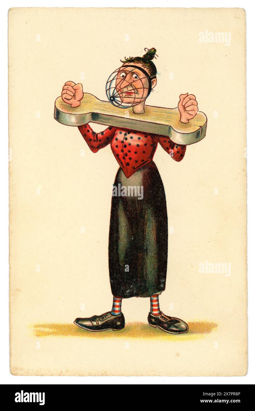 Original and cruel early 1900's WW1 era anti-suffragette comic cartoon postcard after illustrator Dudley Buxton,  of  unattractive woman in stocks. with a metal cage / mask over her face, being silenced. Misogynistic imagery.  Possibly German, circa 1916 Stock Photo