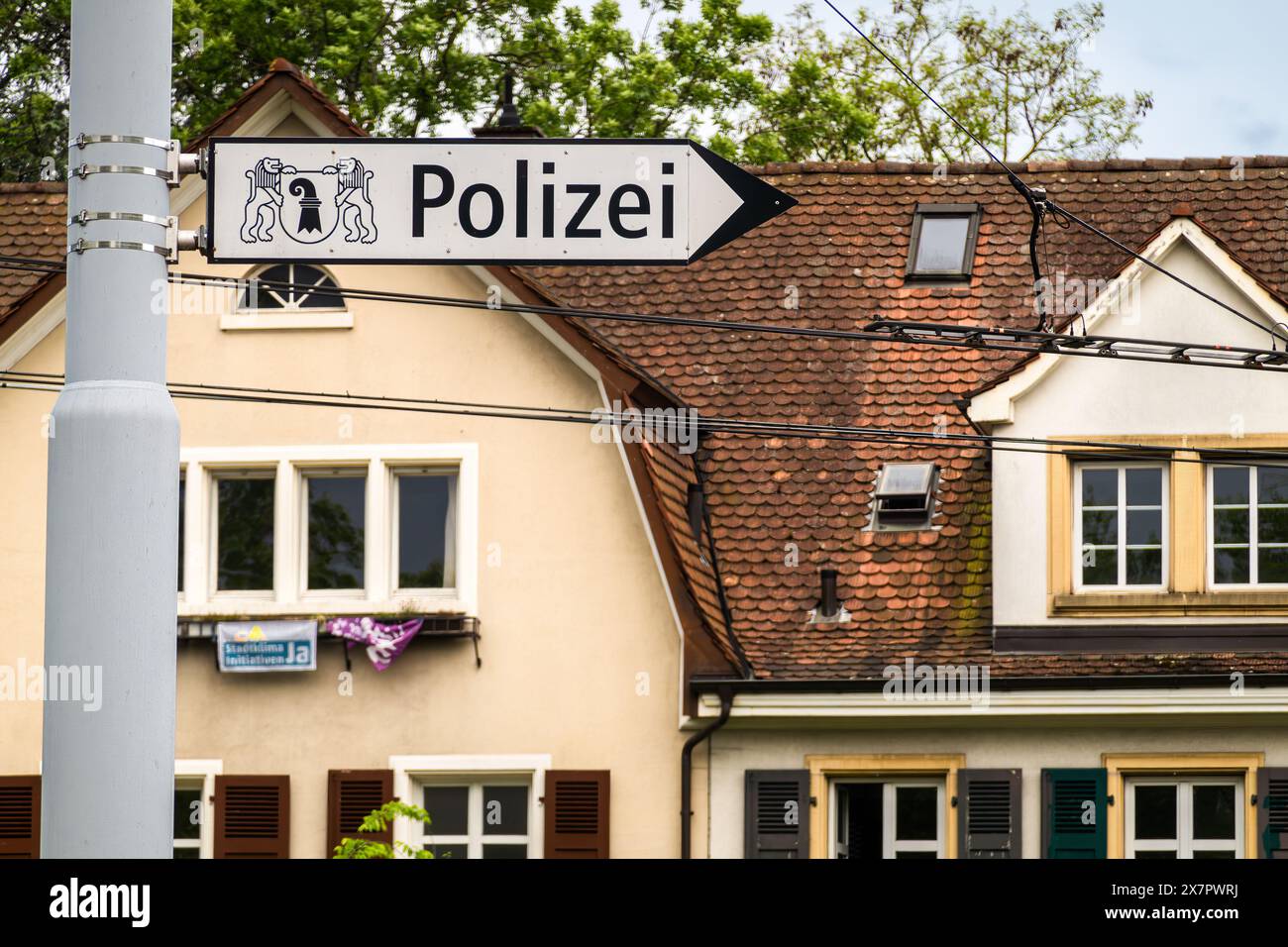 Basel, Switzerland - May 18, 2024: The image shows a german street sign Polizei pointing to a police station, with a building behind. Stock Photo