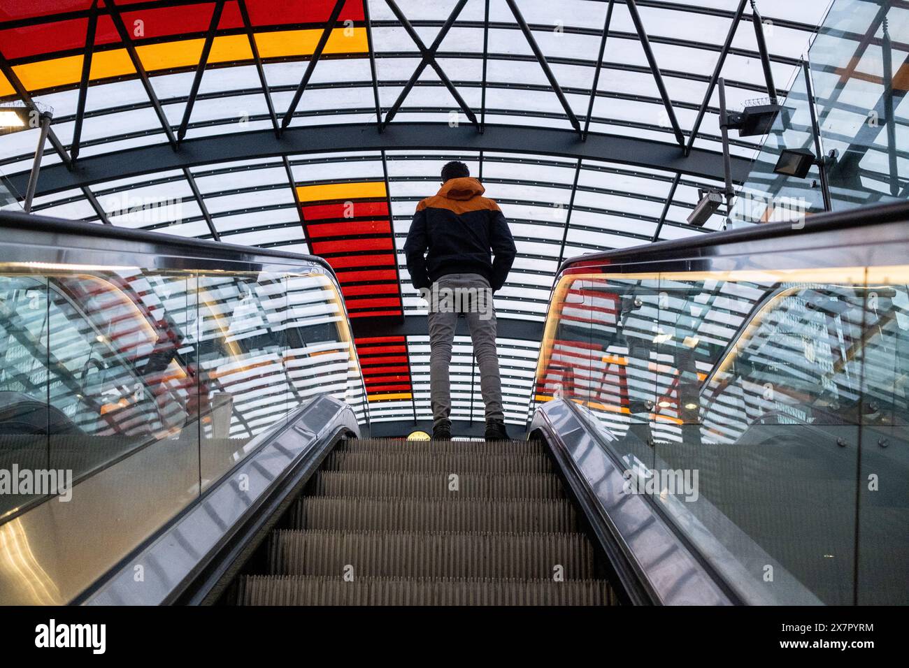 A person at the top of an escalator at the central station officially named Amsterdam-Central in Amsterdam, capital of the Netherlands in Europe on 28 Stock Photo