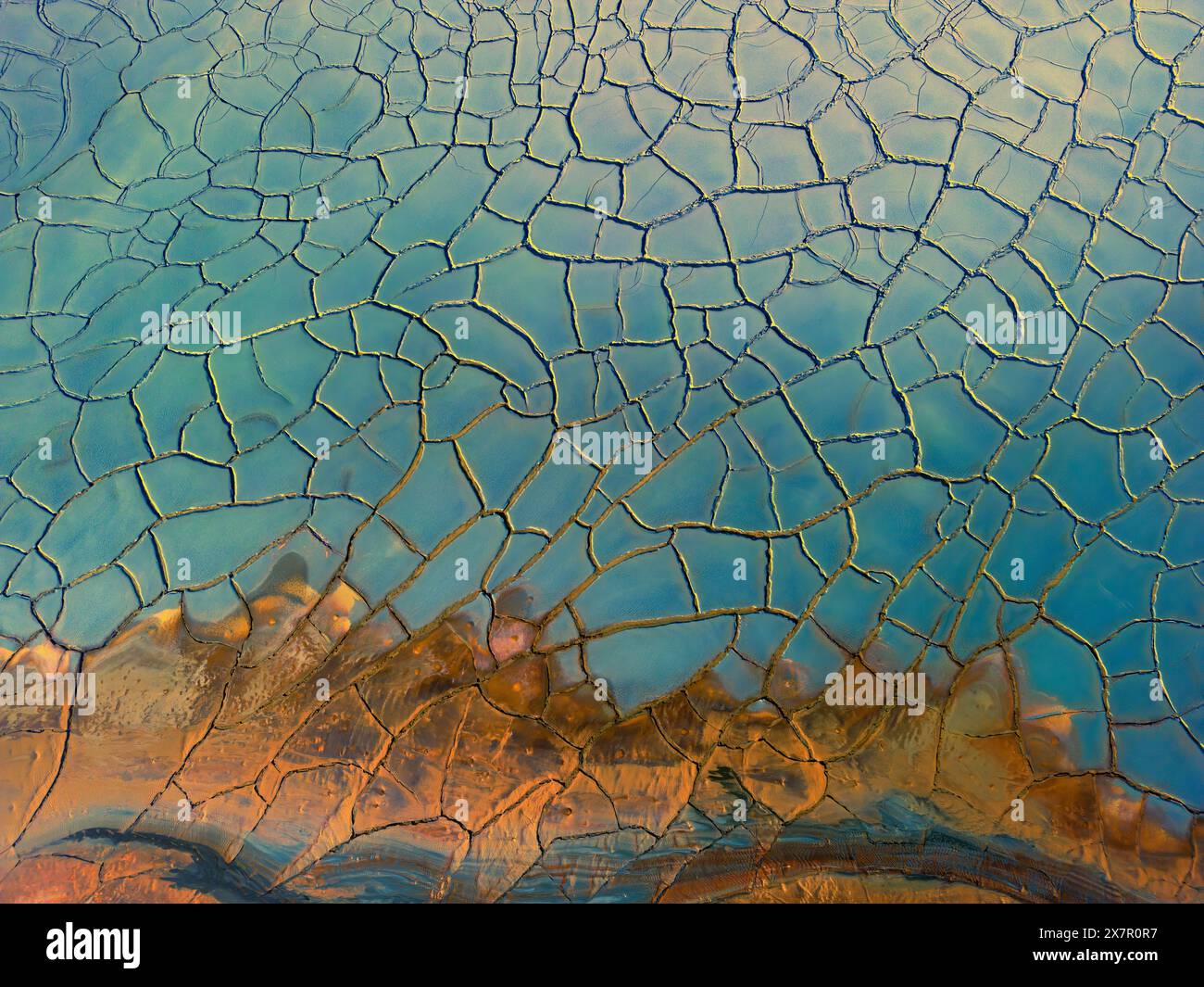 An aerial photograph captures the intriguing textures and contrasting colors of crackled dry mud, showcasing the natural patterns and abstract beauty Stock Photo