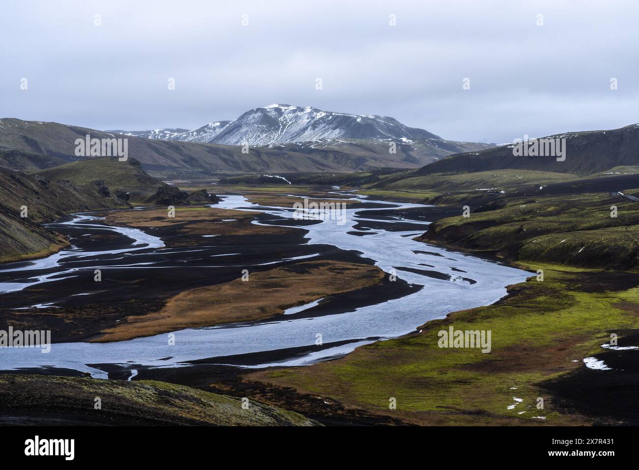 A tranquil river meanders through the verdant valleys and volcanic hills of the Icelandic highlands, showcasing nature's splendor Stock Photo