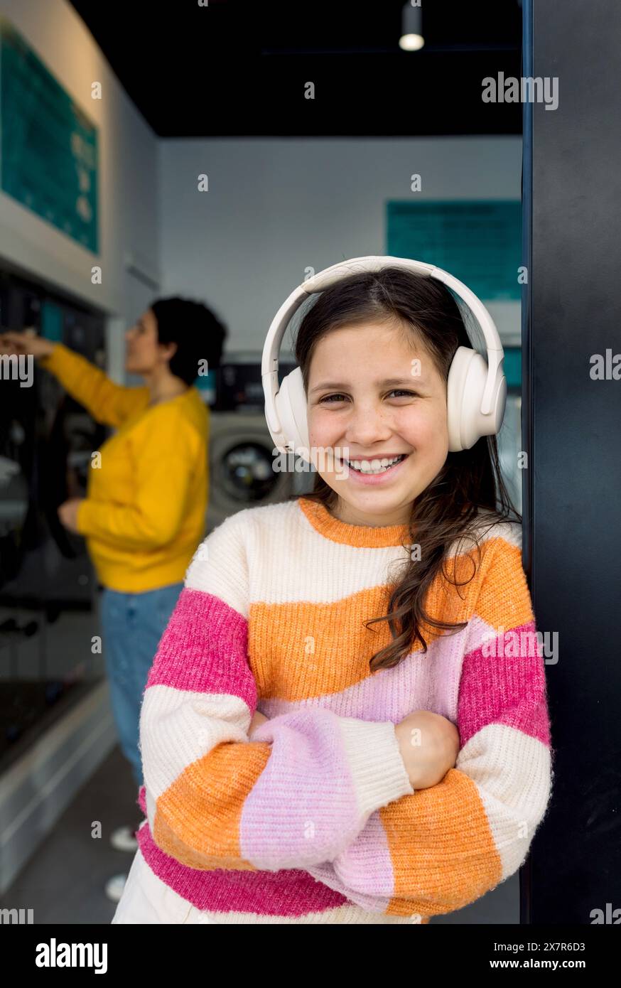 A happy preteen girl wearing headphones smiles looking at the camera ...