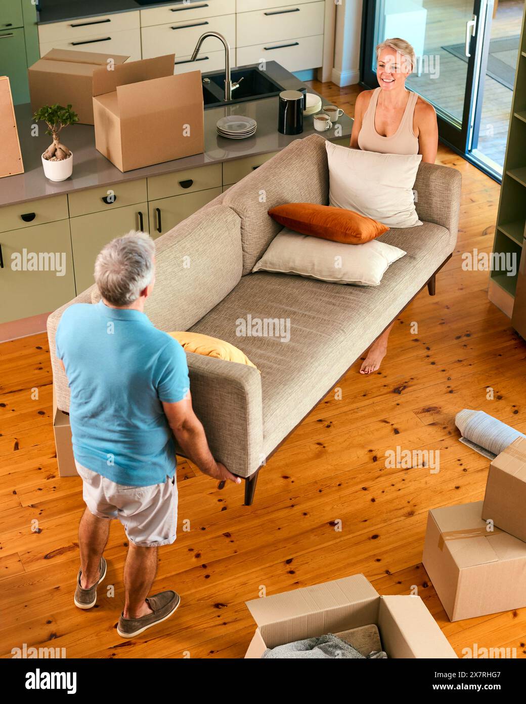 Overhead Shot Of Mature Couple Carrying Sofa Moving Furniture Into New