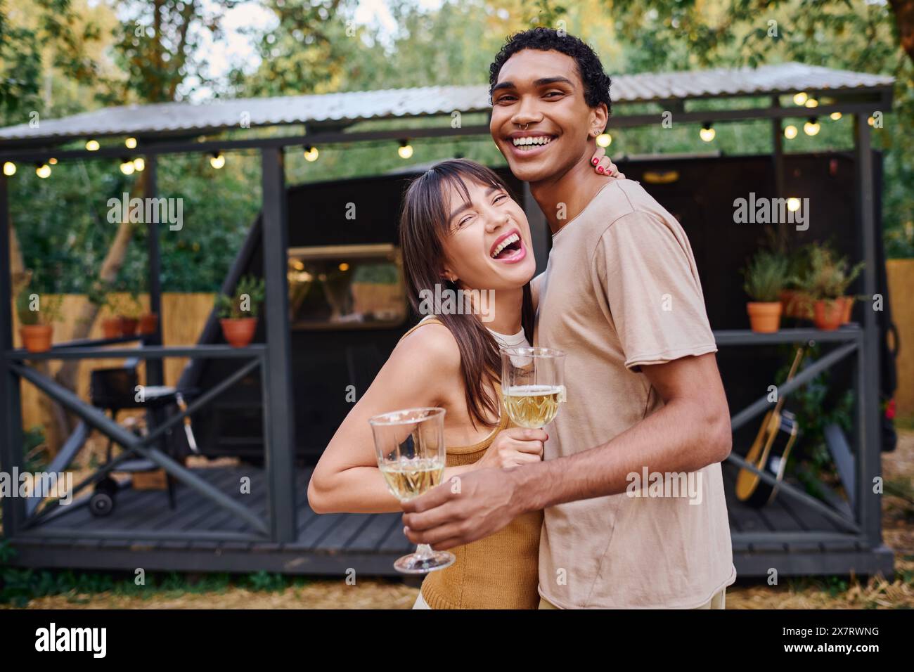 A man and woman hold glasses of wine, enjoying a romantic moment together. Stock Photo