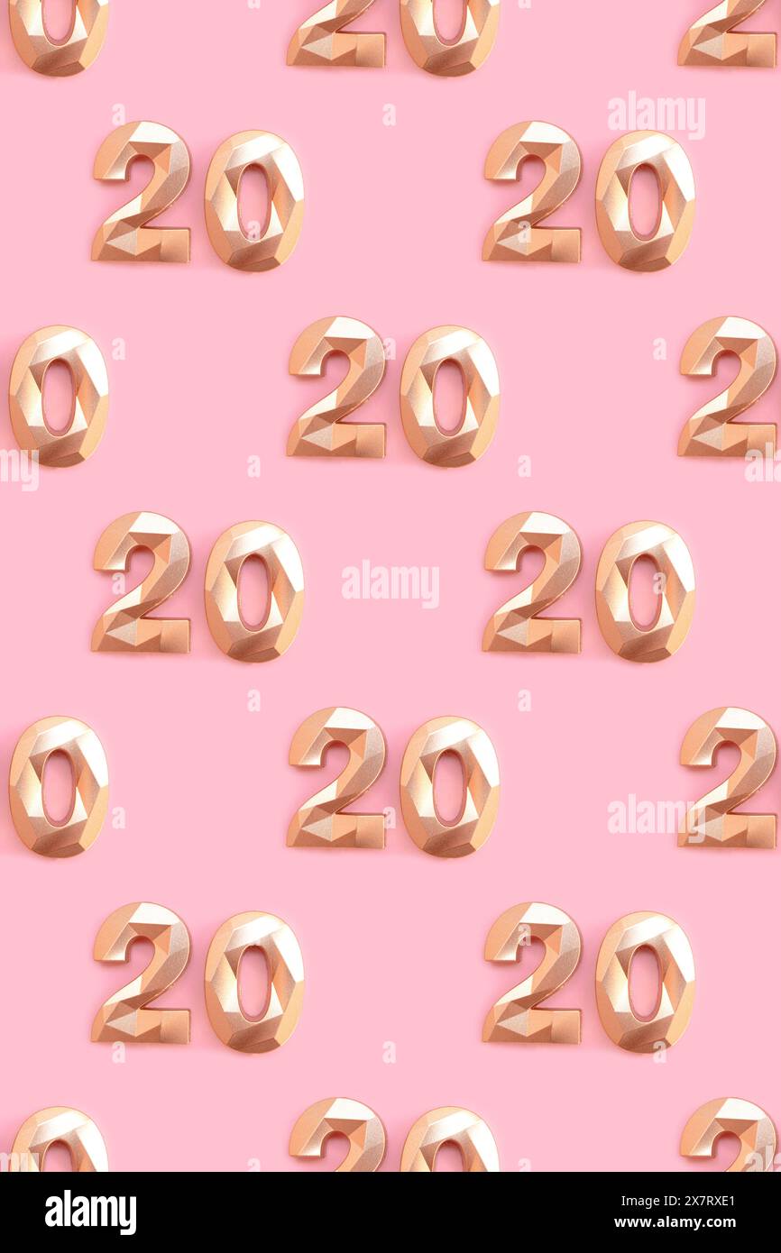 Pattern made of gold colored number 20 on a pink background. Stock Photo