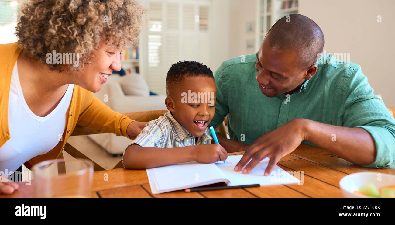 Family Indoors At Home With Grandmother And Father Drawing Picture With Son Stock Photo