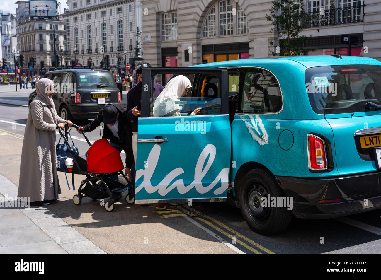 Family enter a London taxi with livery for the Sandals Resort business. Taken on Regent Street, London UK Stock Photo