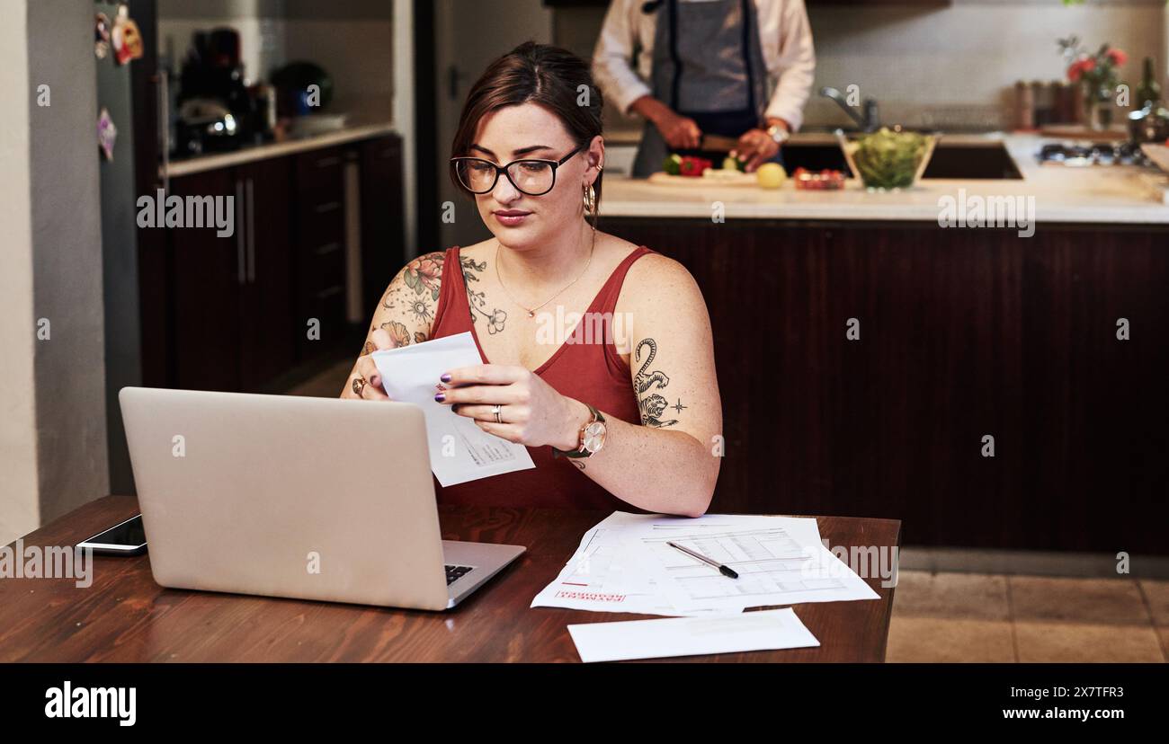 Woman, home and online with bills by laptop for debt management, receipts and invoices for mortgage or rent payments. Girl, internet and open or read Stock Photo