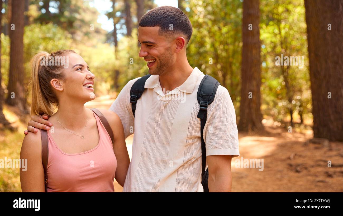 Portrait Of Couple Wearing Backpacks Hiking Along Trail Through Countryside Stock Photo