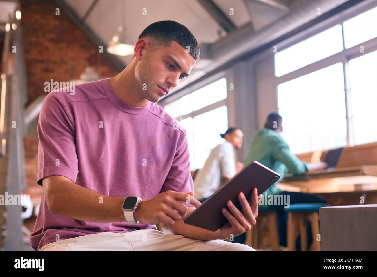 Young Businessman Using Digital Tablet Working In Modern Open Plan Office Stock Photo