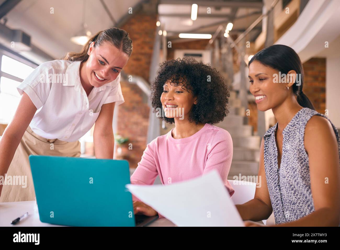 Three Young Businesswomen Meeting In Modern Office Sitting Around Table ...