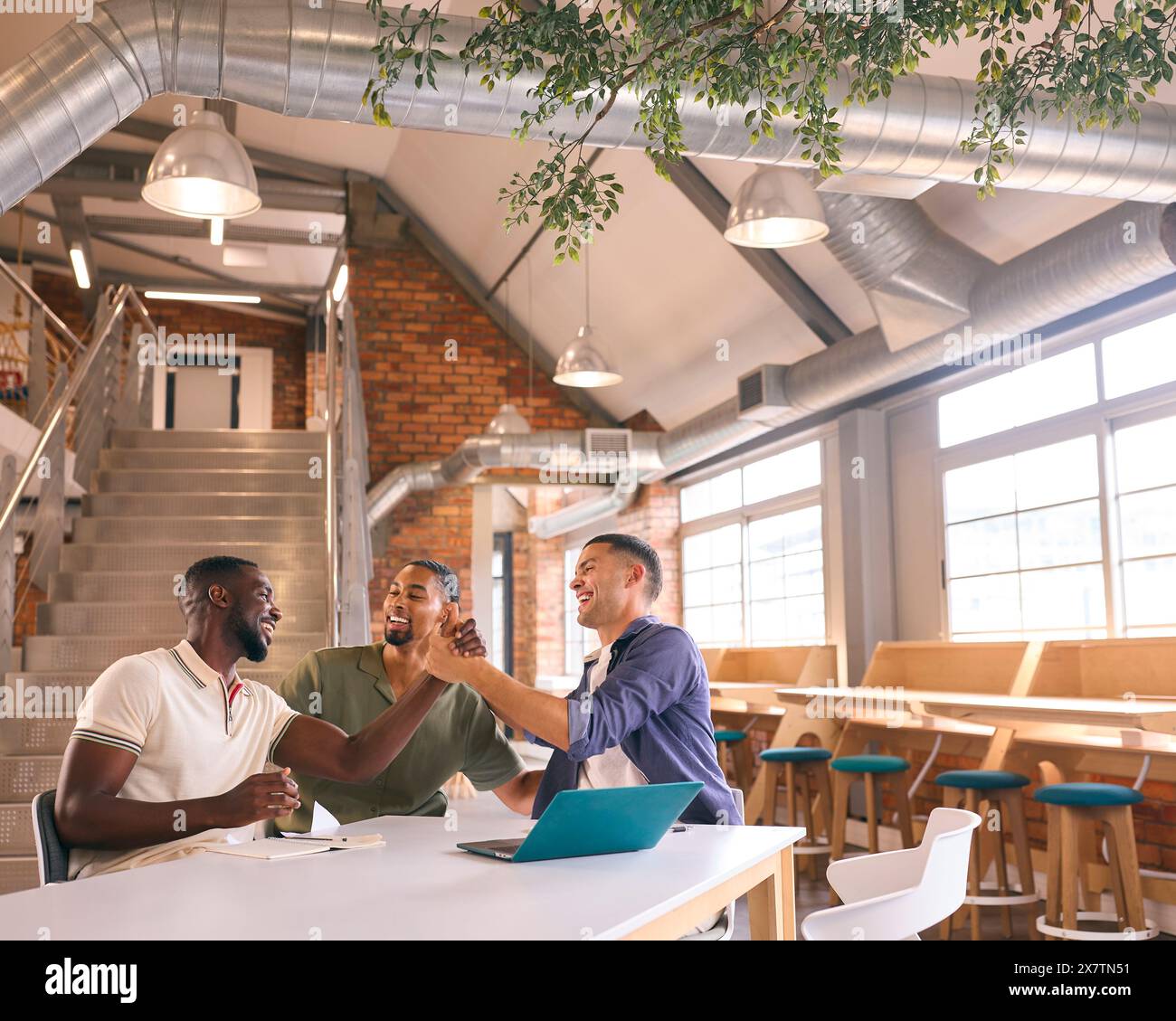 Businessmen Meeting In Modern Office Sitting Around Table Celebrating Shaking Hands Stock Photo