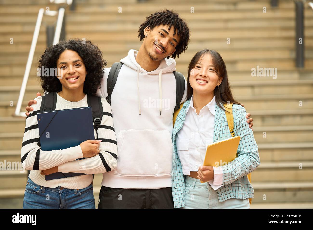 Three young students are smiling and looking to camera Stock Photo
