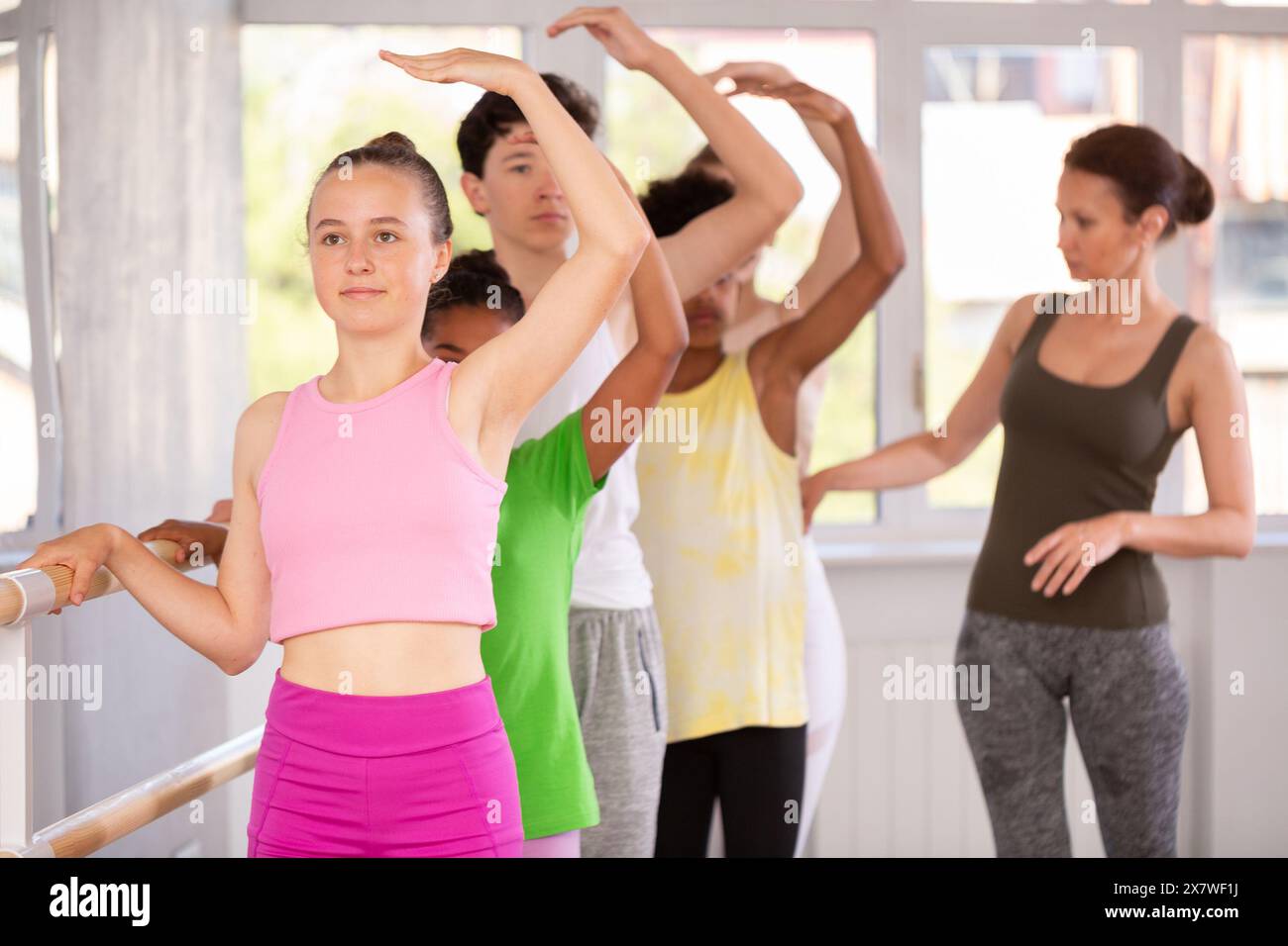 Woman teacher corrects teenagers in first position Stock Photo - Alamy