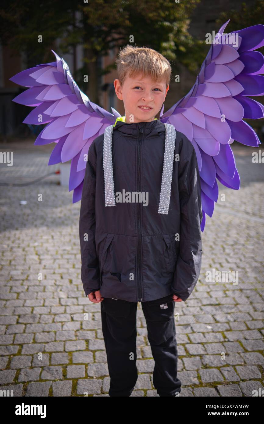 Handsome boy wearing pink angel wings. Teen in black jacket and purple ...