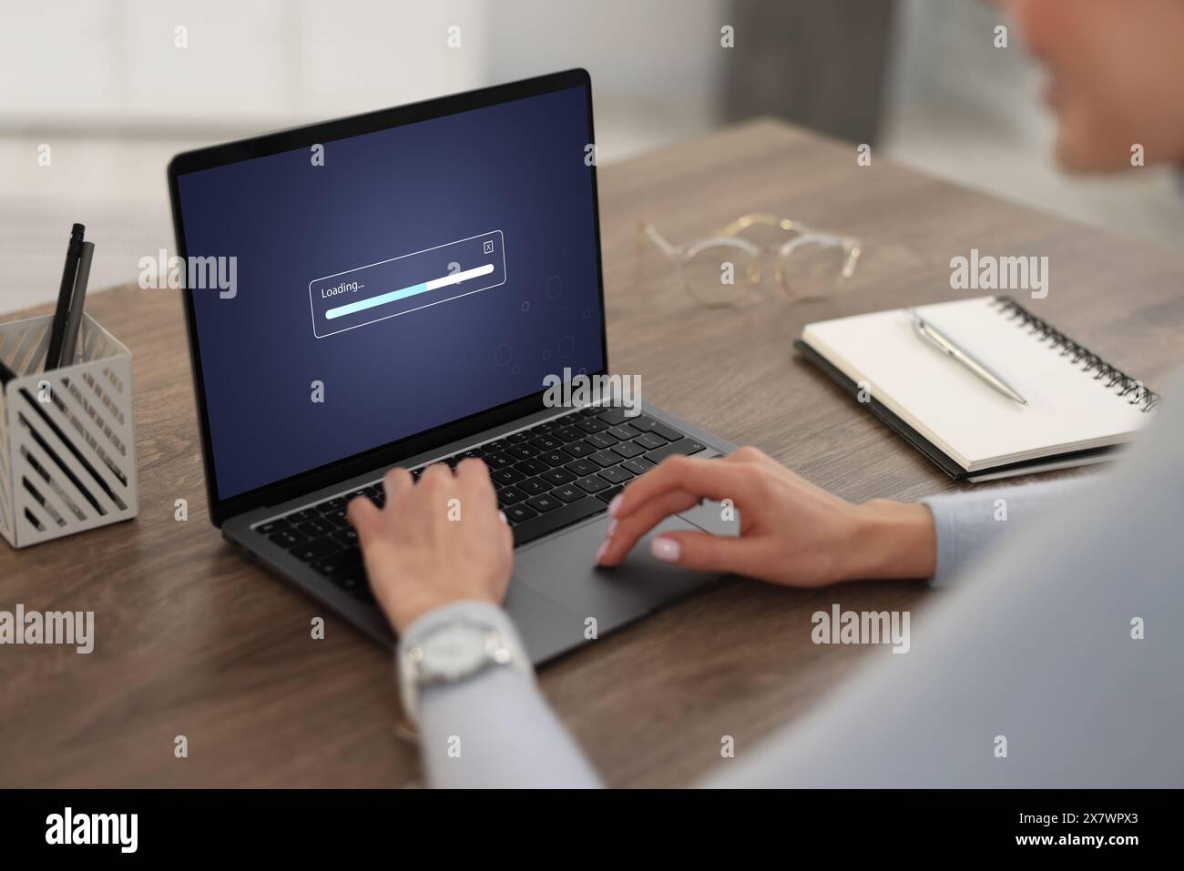 Loading screen displaying progress. Woman working on laptop at table ...