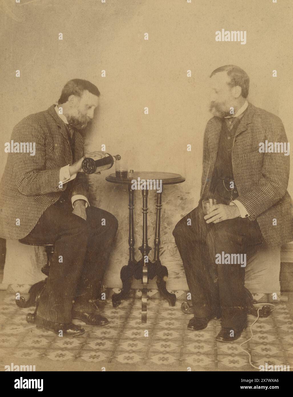 Antique c1890 photograph, brothers drinking whiskey together. They are seven years apart, but look like twins. Exact location unknown, probably Massachusetts or Rhode Island, USA. SOURCE: ORIGINAL PHOTOGRAPH Stock Photo