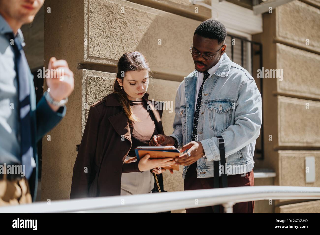 Business professionals discussing project outdoors, focused on digital tablet Stock Photo