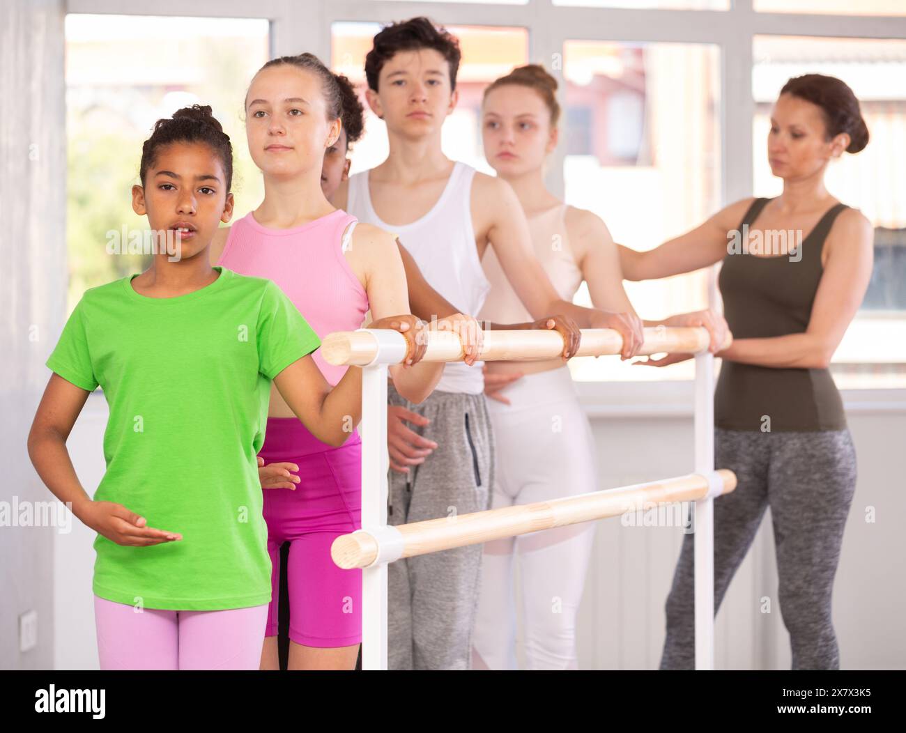 Woman teacher corrects teenagers in first position Stock Photo - Alamy