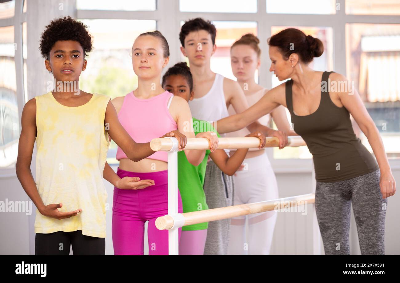 Woman teacher corrects teenagers in first position Stock Photo - Alamy