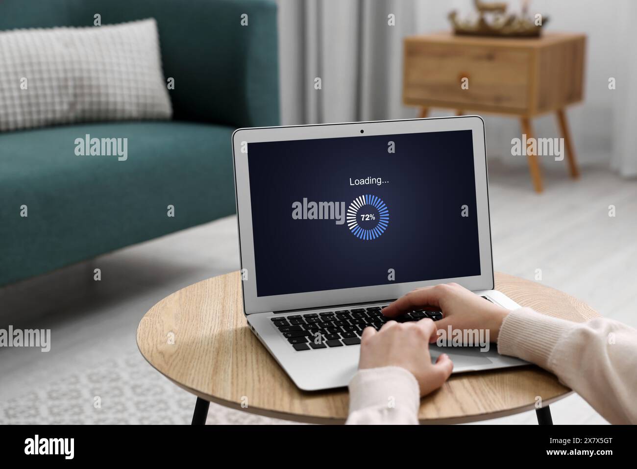 Loading screen displaying progress. Woman working on laptop at table indoors, closeup Stock Photo